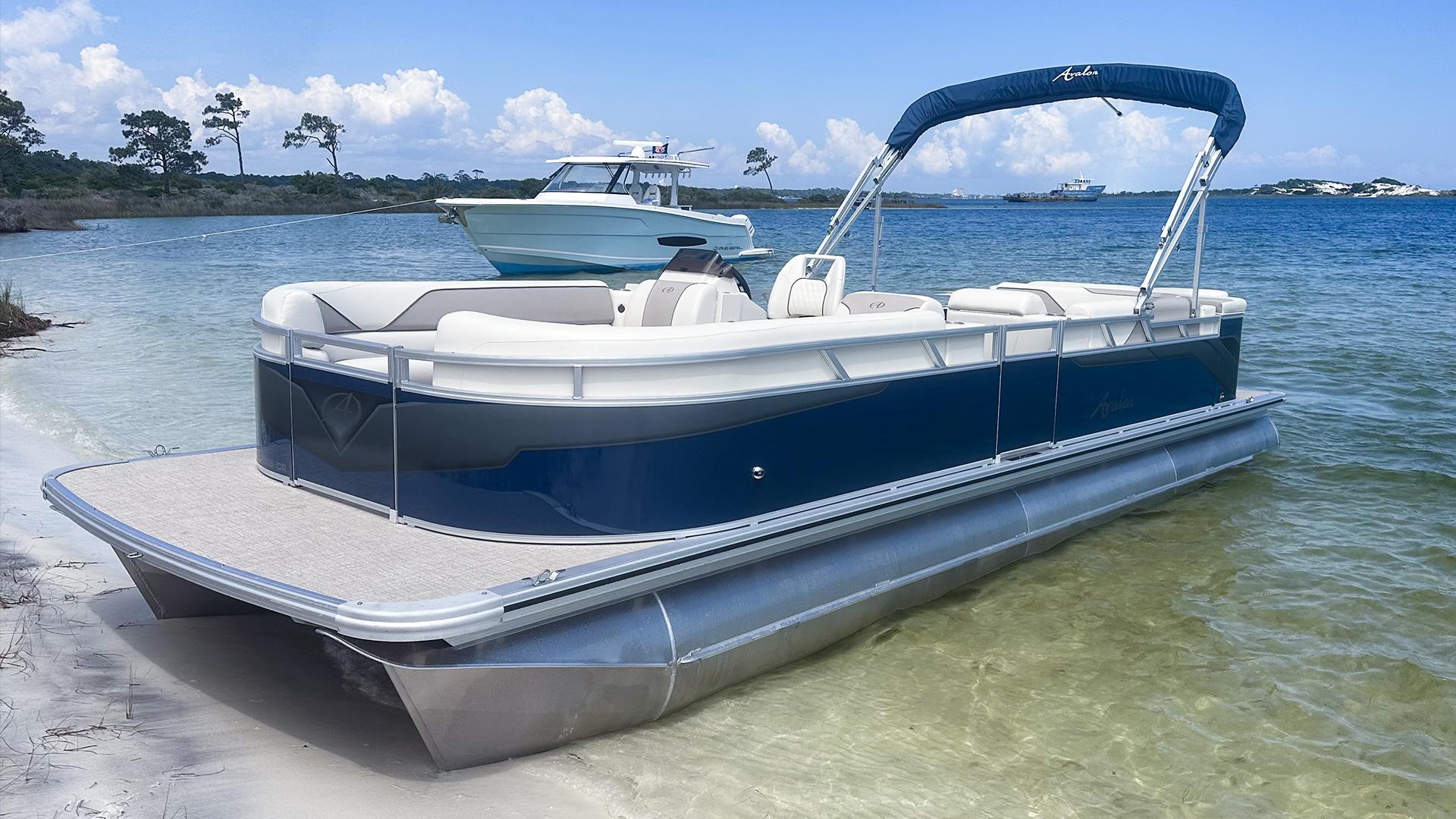 A blue Avalon Pontoon boat beached on a sandy shoreline in Navarre, Florida